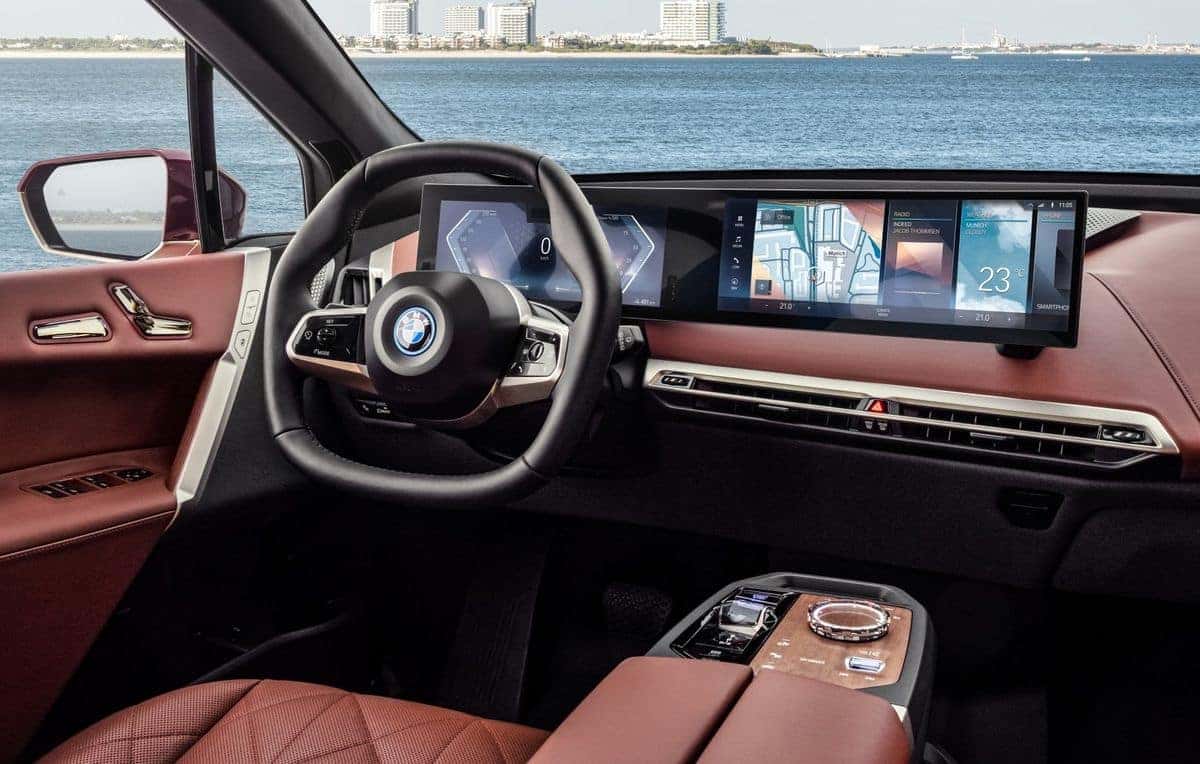 BMW's iDrive system is a central infotainment system. In a car in front of water.