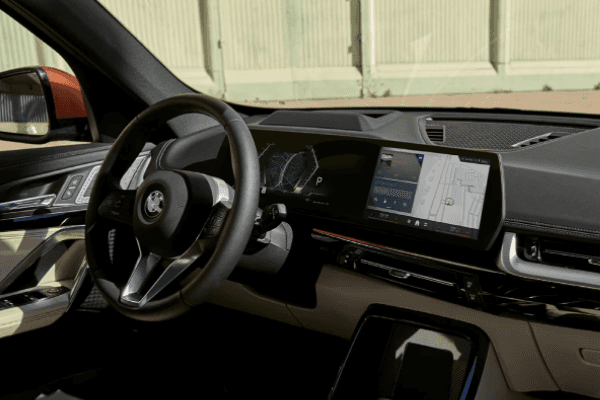 Interior view of the 2025 BMW X1 showcasing the steering wheel and touchscreen display with navigation.