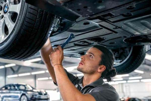 BMW technician working underneath a vehicle on a lift