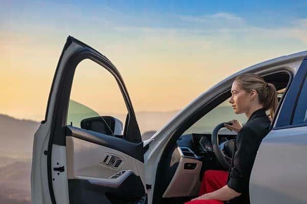 Woman getting into the driver's seat of a BMW at sunset