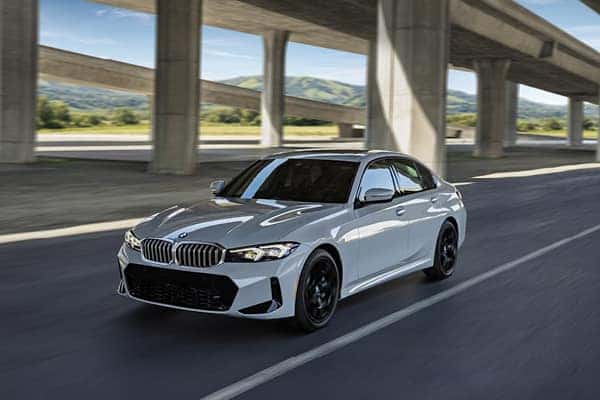 White BMW sedan driving under an overpass