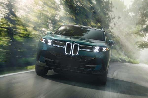 Close-up of a BMW's front grille on a forest road