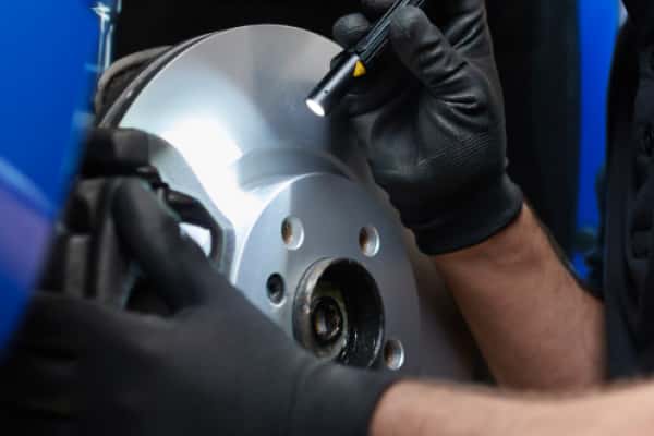 Technician inspecting a brake rotor with a flashlight