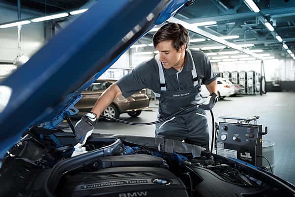 BMW technician working under an open hood