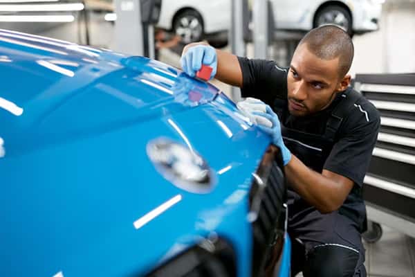 Technician applying paint protection film to a BMW exterior panel