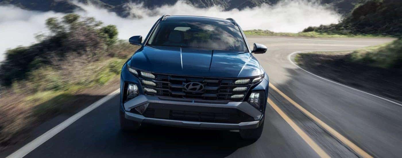 Blue 2026 Hyundai Tucson from the front driving along the coast.