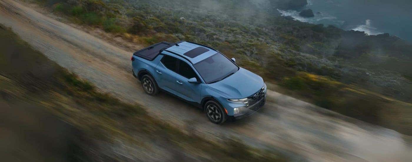 Blue 2022 Hyundai Santa Cruz shown from above driving a dirt road.