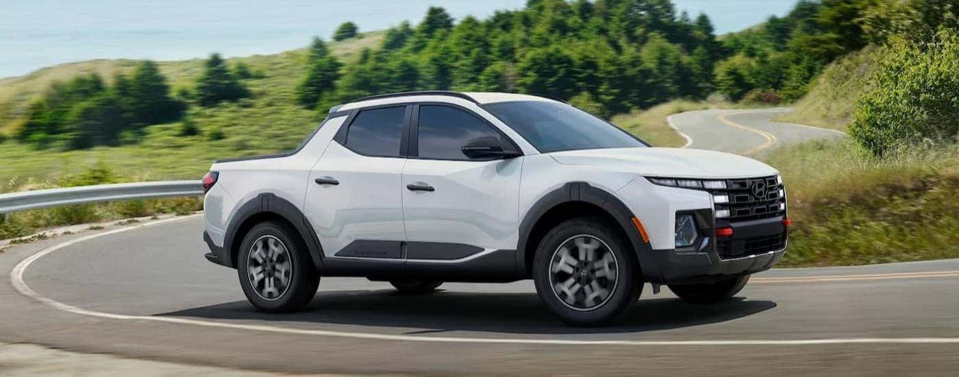 A white 2025 Hyundai Santa Cruz driving on a highway.