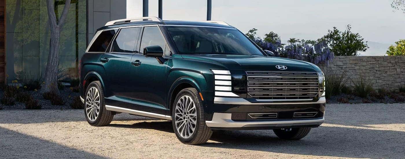 Green 2026 Hyundai Palisade parked off-road in front of a building.