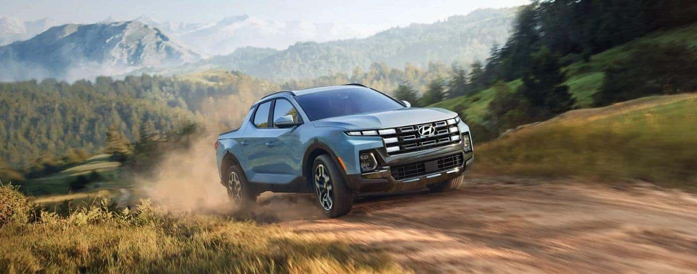 A blue 2026 Hyundai Santa Cruz Limited shown driving a dirt road.