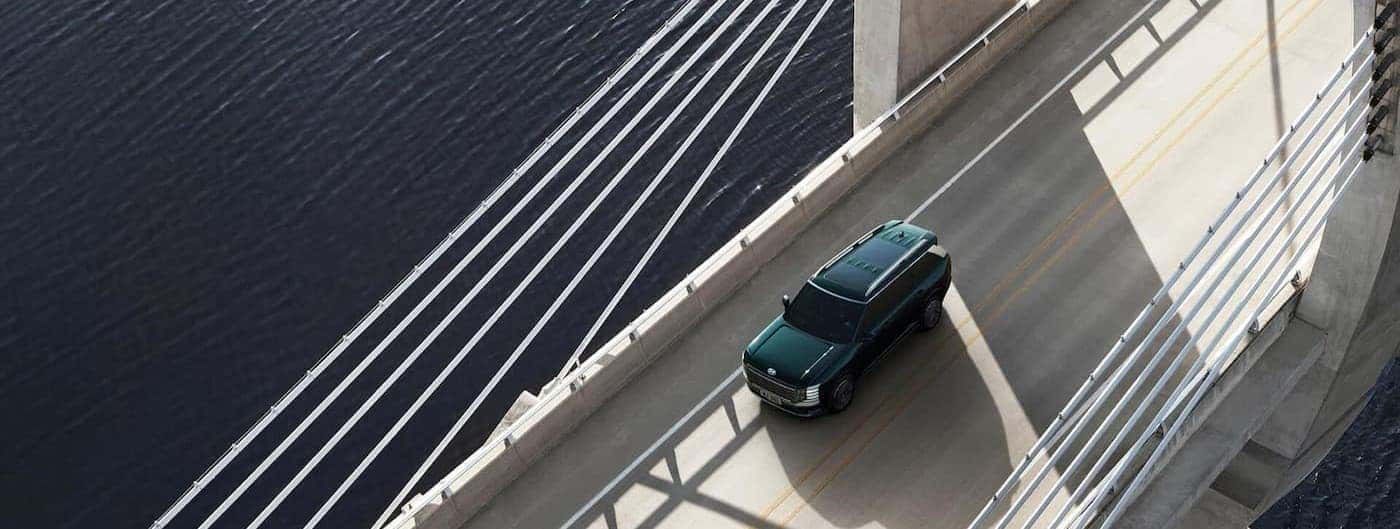 Aerial view of a green 2026 Hyundai Palisade driving on a bridge.