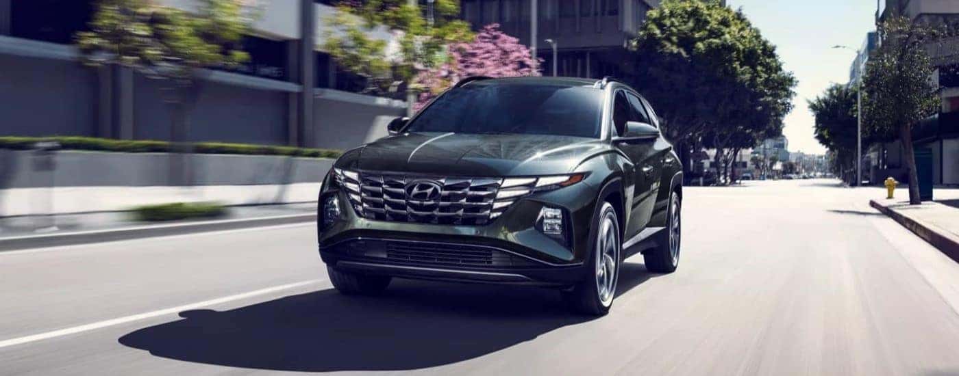 A dark green 2023 Hyundai Tucson Hybrid Limited driving a paved road.