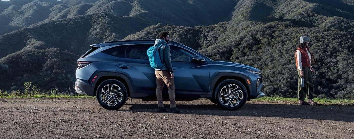 Two hikers near a blue 2025 Hyundai Tucson.