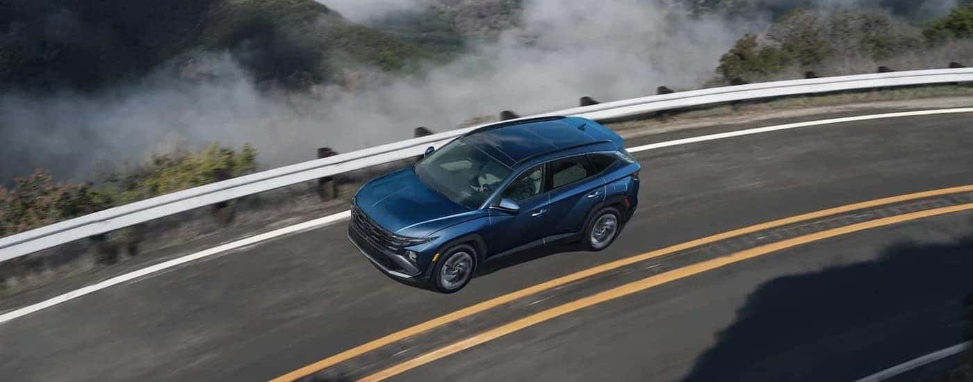 Aerial view of a blue 2026 Hyundai Tucson driving on a highway.