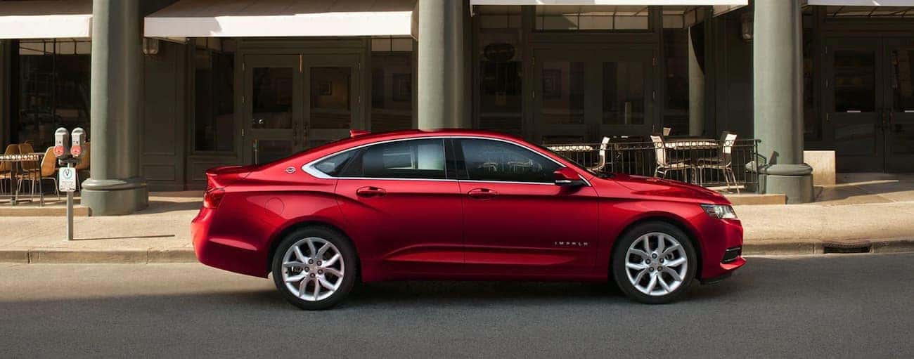 A red 2020 Chevy Impala is parked on a city street in front of a cafe.