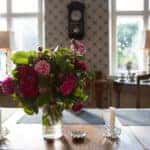 A dinning room with a table with a glass vase holding a bouquet and candles