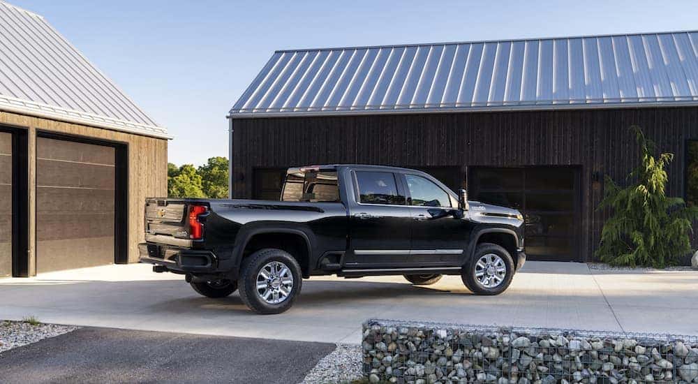 A black 2024 Chevy Silverado 2500 HD High Country is shown from the side while parked in a driveway.