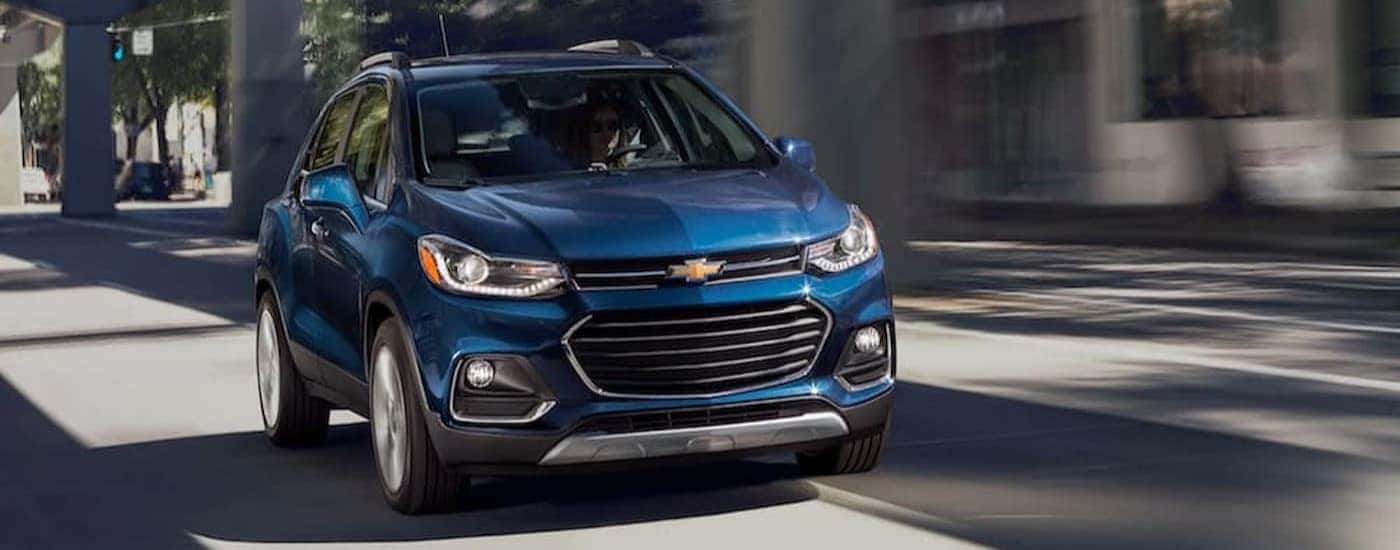 A blue 2020 Chevy Trax is shown driving on a city street.