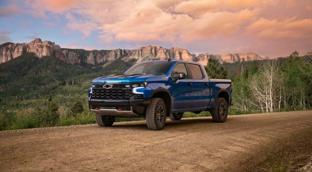 A blue 2024 Chevy Silverado 1500 ZR2 Trail Boss is shown parked off-road.