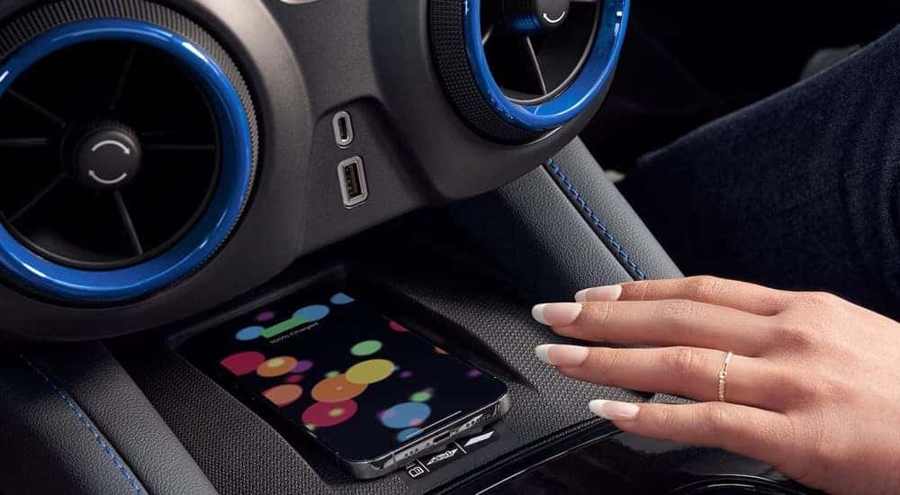 A person is shown using the wireless charging feature in a 2023 Chevy Blazer.