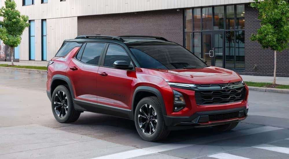 A red 2025 Chevy Equinox RS is shown driving near a building.