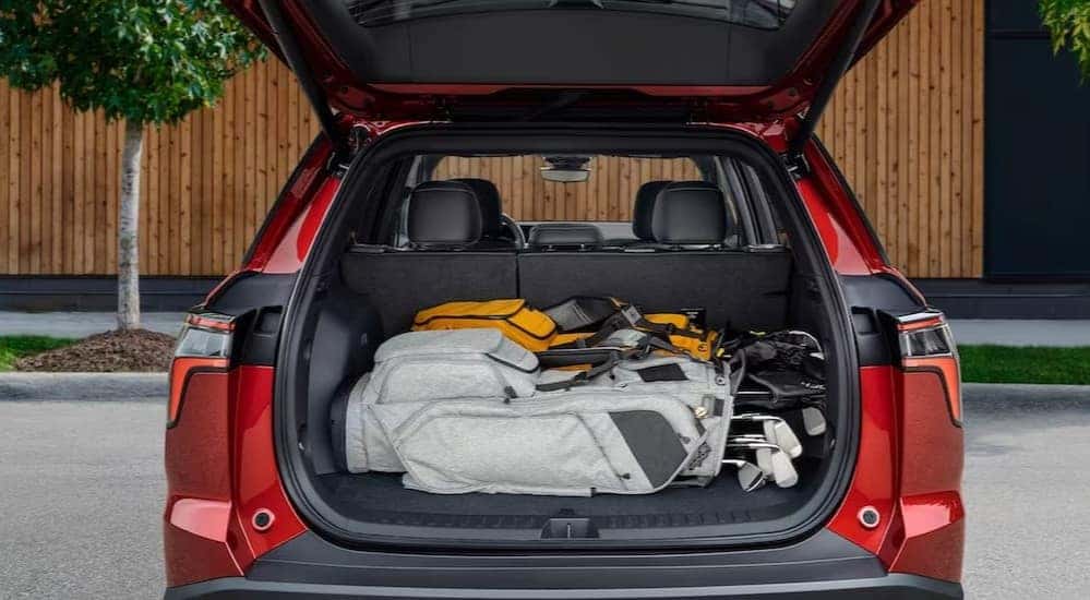 Golf bags are shown in the rear cargo area of a red 2025 Chevy Equinox RS.