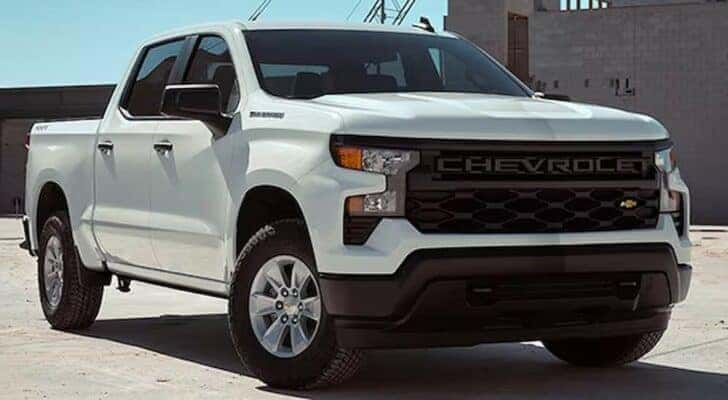 A white 2024 Chevy Silverado 1500 WT is shown parked near a building.