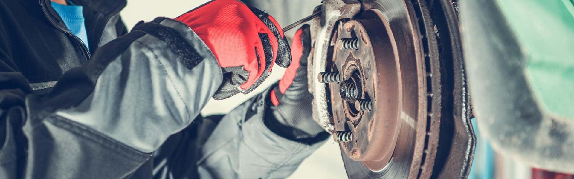 Brake replacement and Safety at Halterman's Toyota of East Stroudsburg | Service Technician Using Screwdriver to Work on Brakes on Vehicle