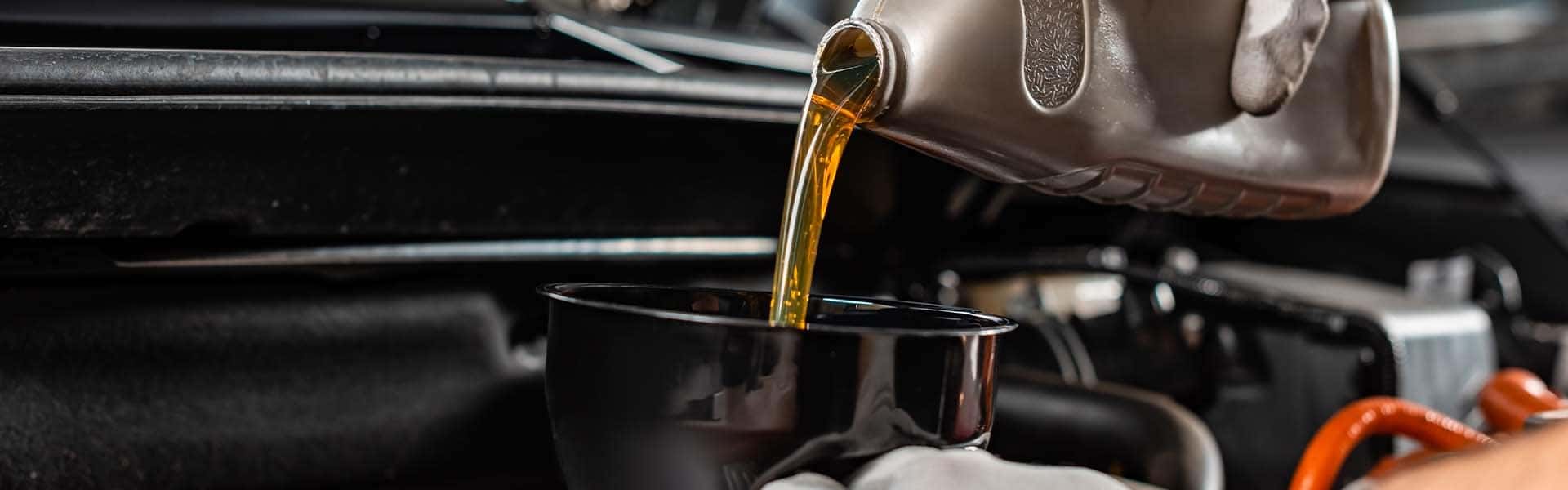 Benefits of Changing Your Toyota’s Oil at Halterman's Toyota in East Stroudsburg | Service Technician Funneling Oil Into Car Engine