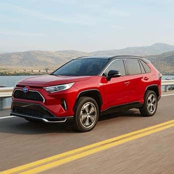 Defining APR at Halterman's Toyota in East Stroudsburg, PA | Red RAV4 drives fast on sunny day past body of water with mountains in background