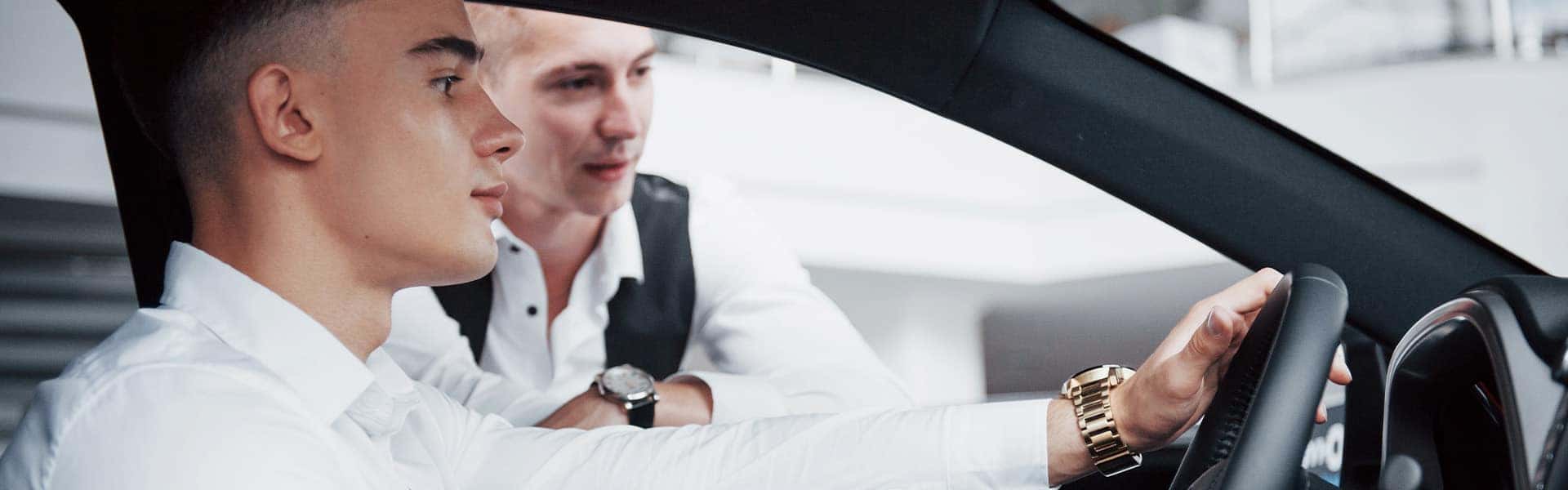 Trade in my leased car at Halterman's Toyota in East Stroudsburg | Customer and Sales Advisor Talking to Each Other While Customer Sits in Vehicle on Showroom Floor