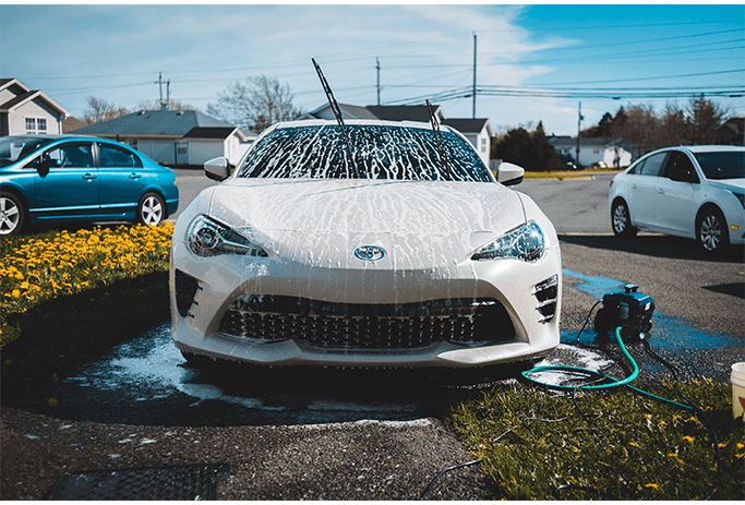 How to Get Your Car Summer Ready at Halterman's Toyota in East Stroudsburg, PA | White Toyota vehicle getting a car wash in person's driveway