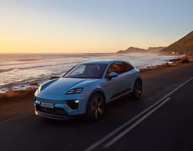 2027 Porsche Macan 4 Electric driving a coastal highway at sunset