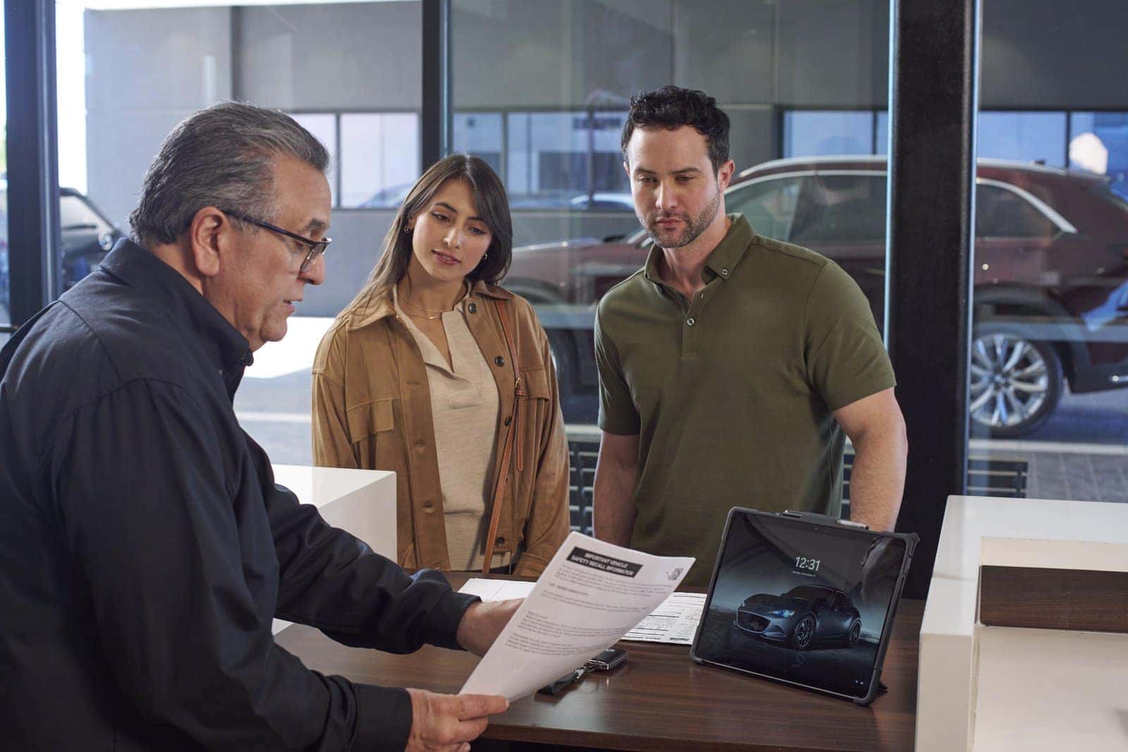 A Mazda of Gladstone sales consultant reviewing vehicle details with customers in the showroom
