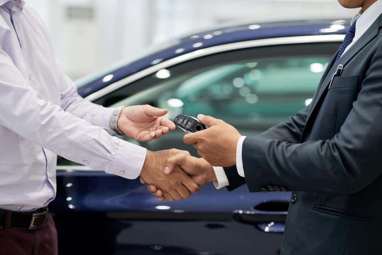 Adult shaking hands at car dealership and buying a car