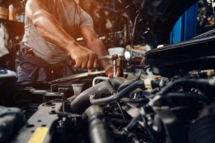 mechanic working on car engine in shop