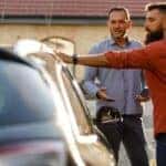 used car salesman showing car to customer