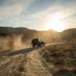 A black pickup truck is climbing uphill on a dirt road. Concept travel offroad with car 4x4