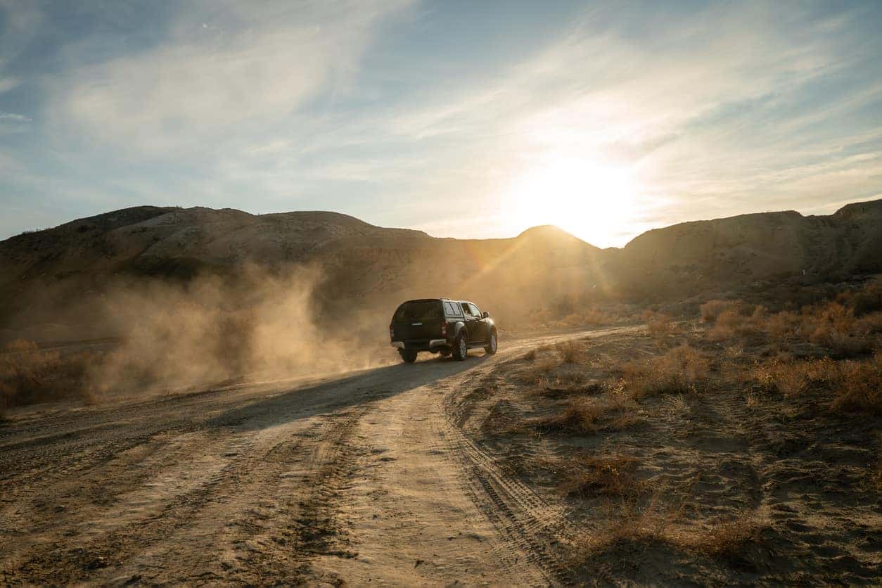 A black pickup truck is climbing uphill on a dirt road. Concept travel offroad with car 4x4