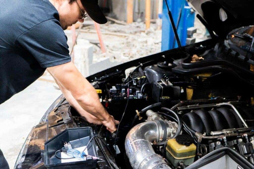 A mechanic inspecting a car engine, checking oil levels and replacing a worn-out air filter.