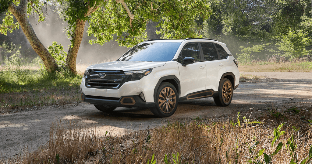 A White Subaru Forester driving in a forested road.