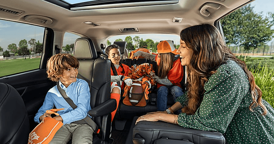 A mom and her three children in a Subaru Ascent, with bags packed for a road trip.