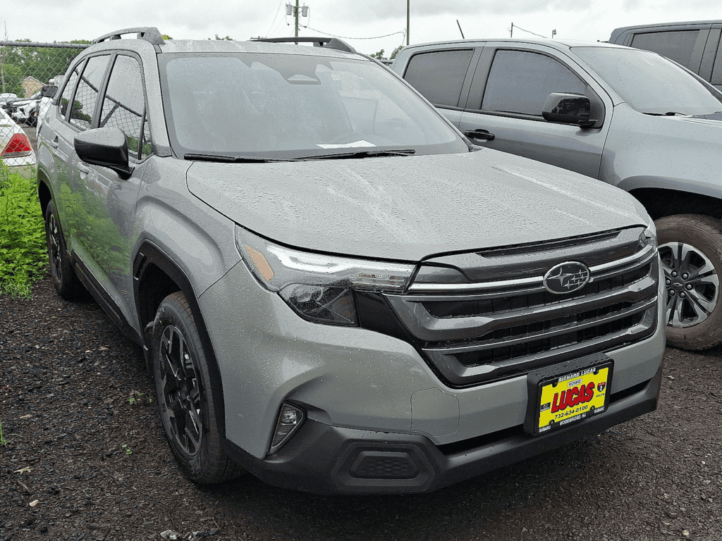 2025 Subaru Forester parked at a dealership lot on a rainy day, featuring a new front grille design and Lucas dealership license plate.