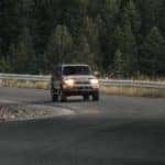 A Toyota Land Cruiser driving along a mountain road with forested trees all around.