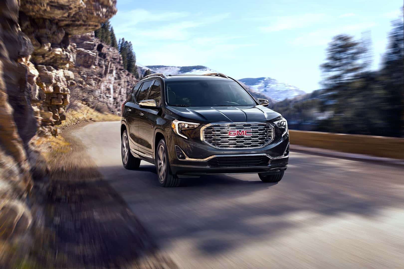 2021 GMC Terrain Denali Exterior in Graphite Gray Metallic with (RT7) 19" Ultra-Bright Machined Aluminum Wheels; 3/4 Passengers side Front; Road shot/motion; Mountains in background; Vail, Colorado Location.