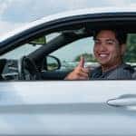 man driving silver car thumbs up