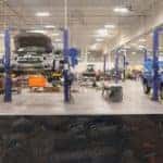 two trucks being serviced on power lifts in an auto shop