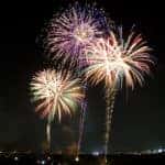 Multicolored fireworks going off over a city skyline at night.