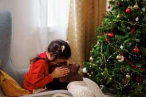 girl opening presents next to a christmas tree