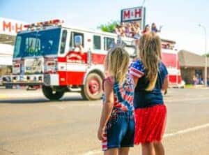 Two little girls watching a firetruck drive by at a Fourth of July Parade